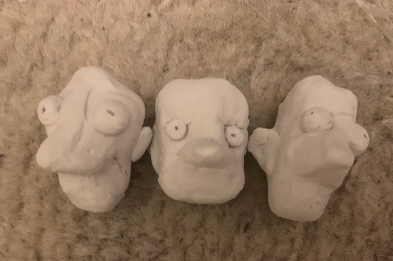 Three clay modeled faces by Derin Oesch